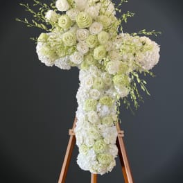 White and pale green floral cross on a wooden stand