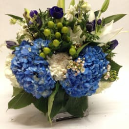 Blue and white floral arrangement in a square glass vase