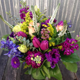Mixed bouquet with purple, pink, and yellow flowers in a vase