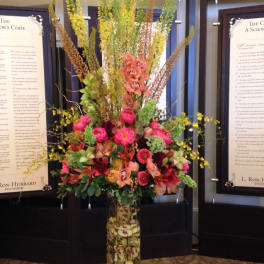 Tall mixed floral arrangement in a clear glass vase with pink and orange blooms