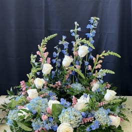 Large floral arrangement with white roses, blue blooms, and pink accents