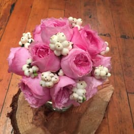Pink rose bouquet with white berry accents in a small glass vase