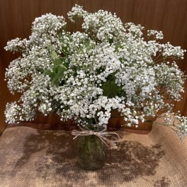 White baby's breath bouquet in a glass vase with a ribbon