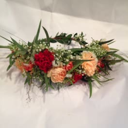 Low floral arrangement with red and peach carnations and greenery