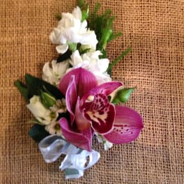 Pink orchid corsage with white flowers and a silver ribbon
