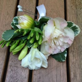 Small floral corsage with white and pale pink blooms on a ribbon tie