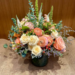 Mixed bouquet of peach and cream roses in a dark vase