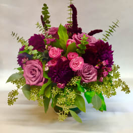 Bouquet of pink and purple roses with greenery in a vase