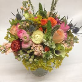 Mixed bouquet in a gray vase with pink, orange, yellow, and green blooms