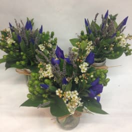 Three small blue-and-white floral arrangements in glass jars