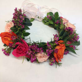 Floral wreath with pink, orange, and purple blooms on a white ribbon base