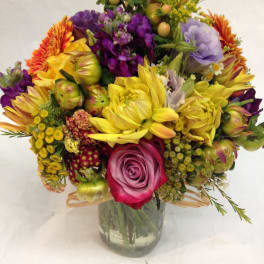 Colorful mixed bouquet in a clear glass vase with roses and daisies