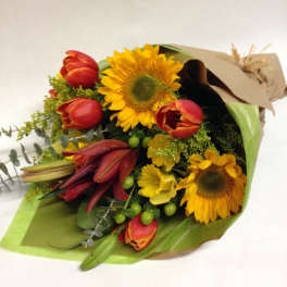 Bouquet of sunflowers, red tulips, and yellow lilies wrapped in paper