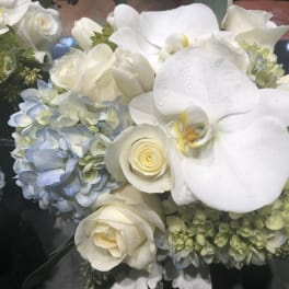 White orchids and roses with blue hydrangeas in a bouquet