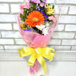 Colorful mixed bouquet with a large orange gerbera daisy and pink ribbon wrap