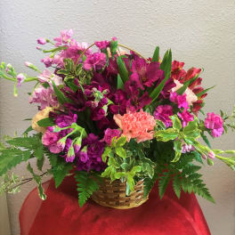 Mixed pink and purple flowers arranged in a wicker basket