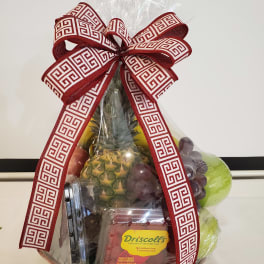 Fruit basket wrapped in clear plastic with a red patterned bow