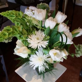 White tulips and spider mums arranged with green blooms in a vase.