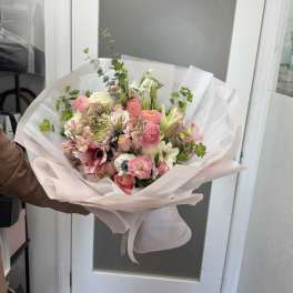 Hand-tied bouquet of pink and white mixed flowers wrapped in pale paper