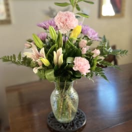 Mixed bouquet of pink and purple flowers in a glass vase