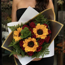 Bouquet of red roses and yellow sunflowers wrapped in white and brown paper
