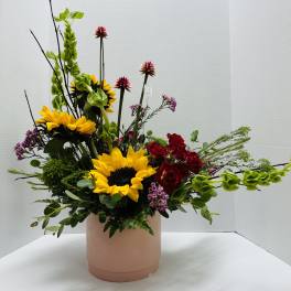Sunflower and red rose arrangement in a blush cylindrical vase