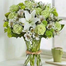 Green and white bouquet with lilies and roses in a glass vase