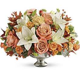 Peach roses and white lilies arranged in a silver pedestal vase