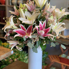 Bouquet of pink and white lilies in a tall white vase