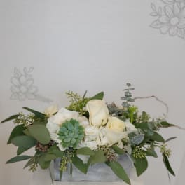 White roses and succulents arranged in a low rectangular container