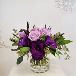 Purple and pink rose bouquet in a clear glass vase