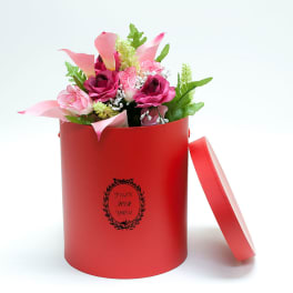 Pink and magenta flowers in a red gift box with a lid