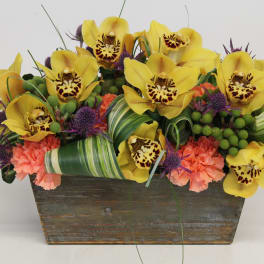 Yellow orchids and pink carnations in a rustic wooden planter