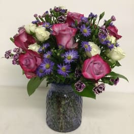 Pink and white roses with purple daisies in a glass vase