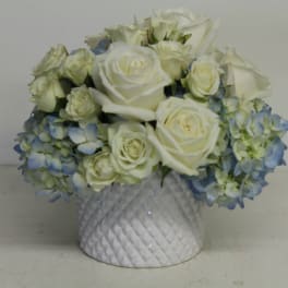 White roses and blue hydrangeas in a white textured vase