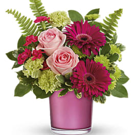 Pink roses and magenta daisies in a pink glass vase