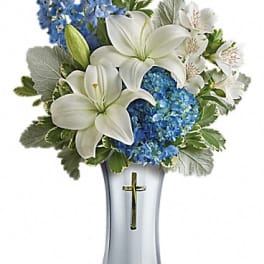White lilies and blue flowers arranged in a silver vase