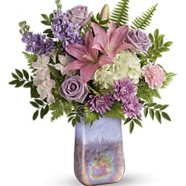 Bouquet of pink lilies, lavender roses, and purple flowers in a tall vase