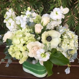 White and pale green floral arrangement in a green-striped container