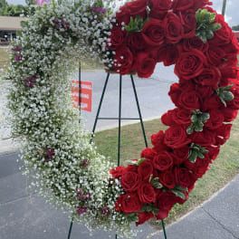 Heart-shaped floral wreath with red roses and white baby's breath on an easel