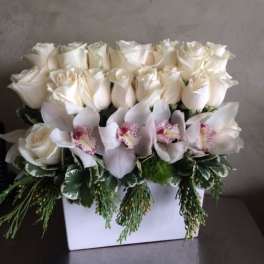 White roses and pale orchids arranged in a white box