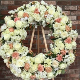 Large floral wreath of white and blush blooms on a wooden easel