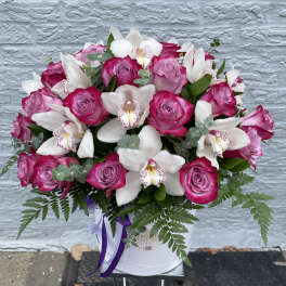 Pink roses and white orchids arranged in a white hat box