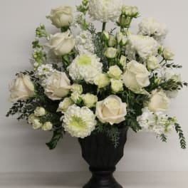 White roses and chrysanthemums arranged in a black urn vase