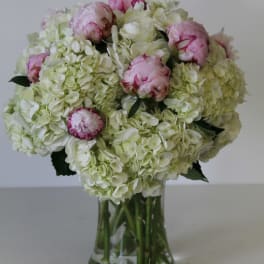 Pink peonies and white hydrangeas in a clear glass vase