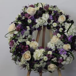 Floral wreath with white roses and purple flowers on an easel