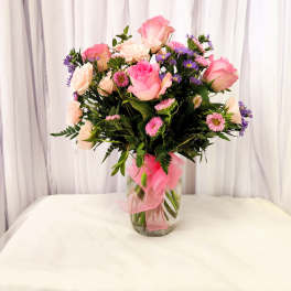 Pink and white roses with purple daisies in a glass vase