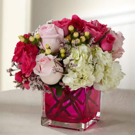 Pink and white rose bouquet in a pink glass vase