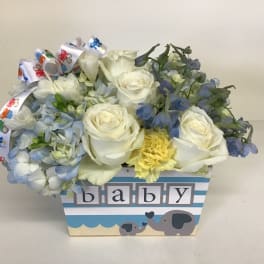 White roses and blue flowers in a baby-themed box with elephant graphics