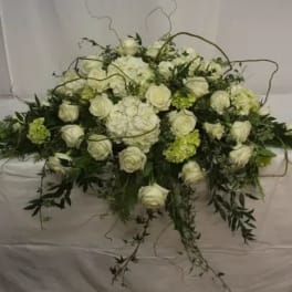 White rose and hydrangea floral arrangement with trailing greenery